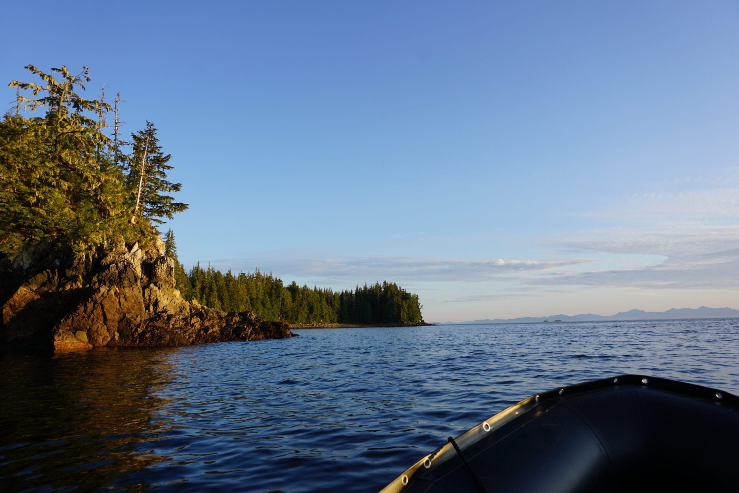 Bow of Zodiac at sunset in front of a forested island